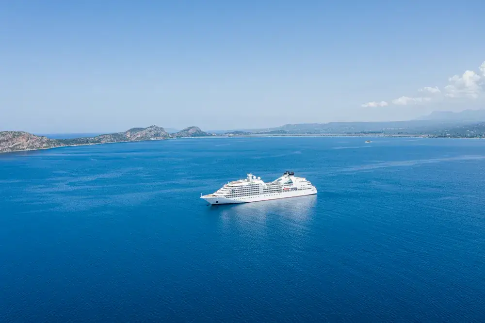Una nave da crociera bianca sul mare blu davanti alla costa